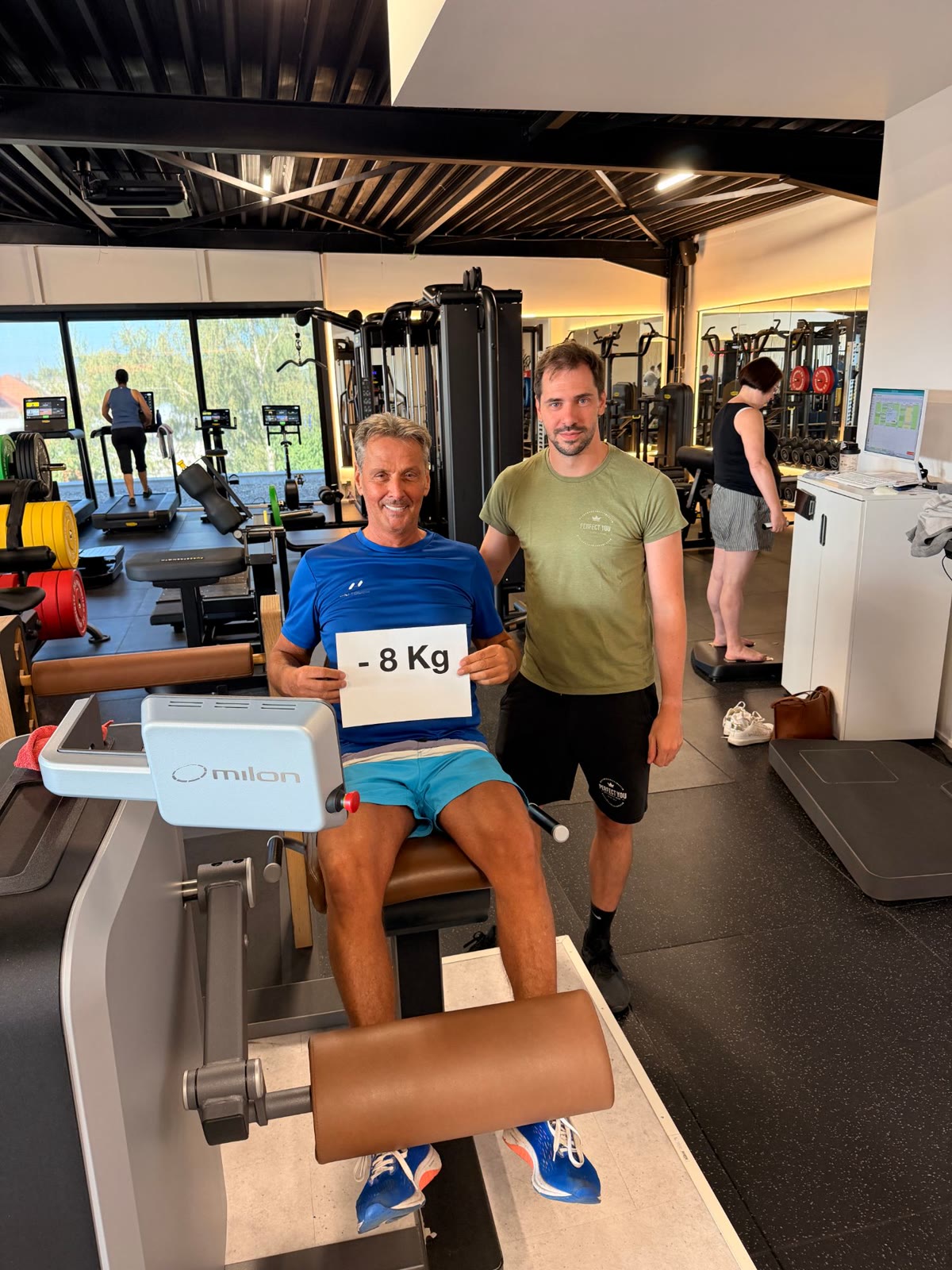 Eric met bordje -8 kg naast zijn coach